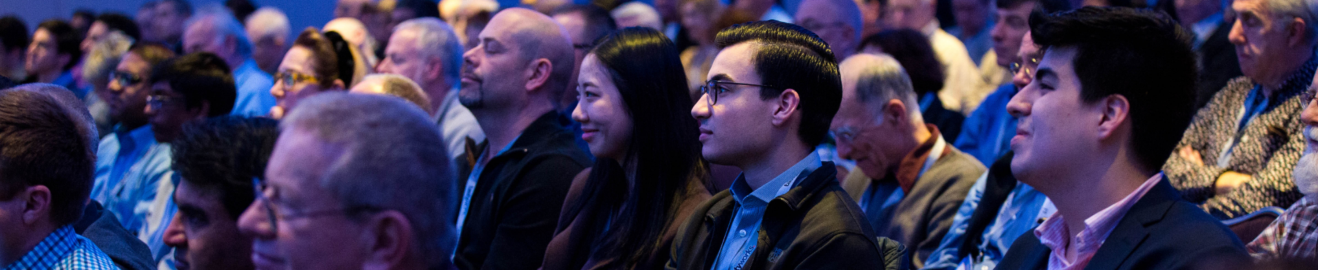 A large image of attendee's  watching events at the conference